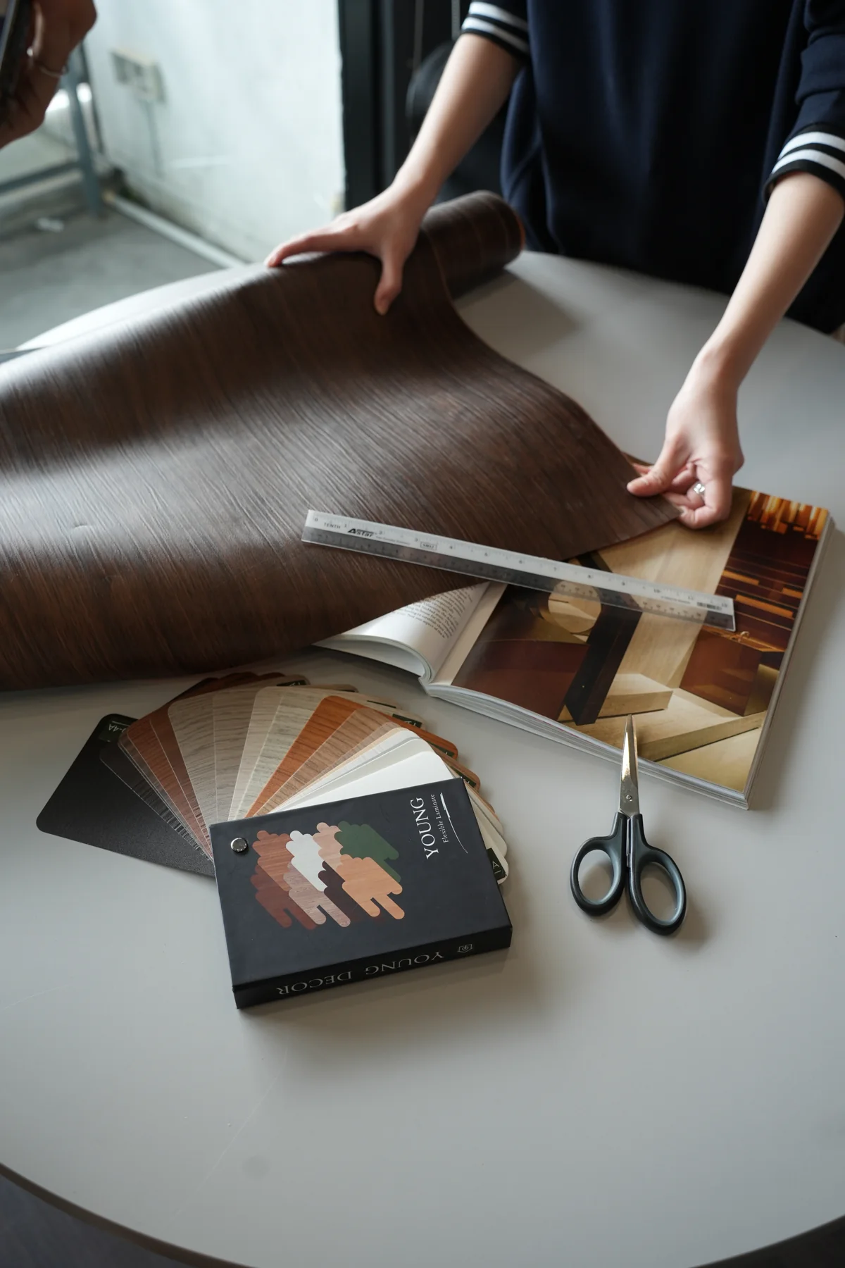 Young Laminate sheet being unrolled and measured beside decor samples
